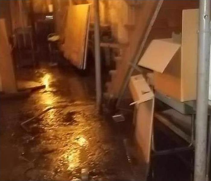 Basement with water damage with chairs and boxes 
