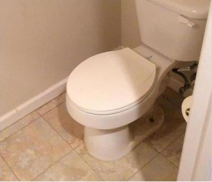 Toilet in a bathroom with tile floor and white baseboards