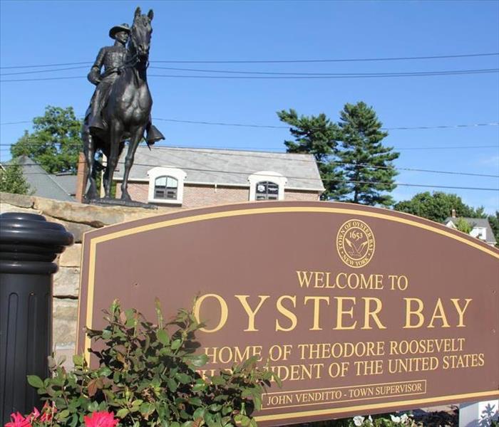 Oyster Bay township sign and Theodore Roosevelt Memorial in the background.